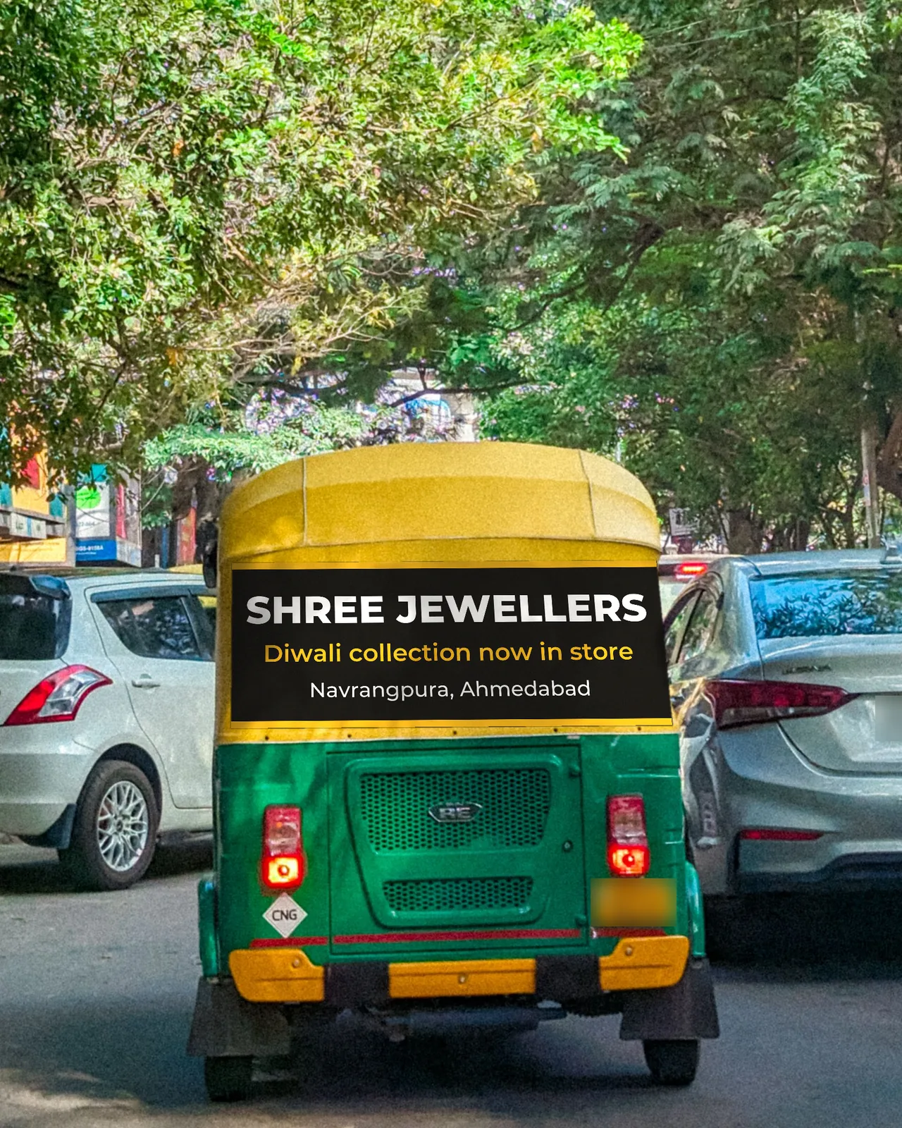 The back of a green and yellow CNG auto in traffic, with a sample jewellery shop banner across the back of its yellow hood.